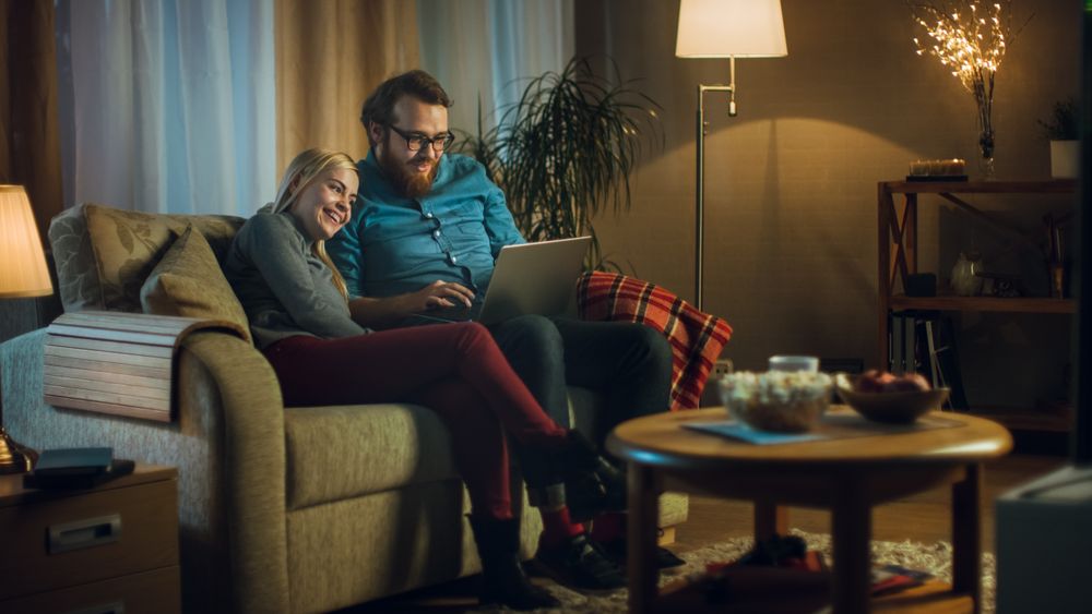 Girlfriend and Boyfriend Sitting on a Sofa with Laptop on His Knees