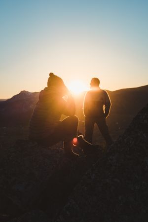 Man and woman enjoying sunset in autumn mountains