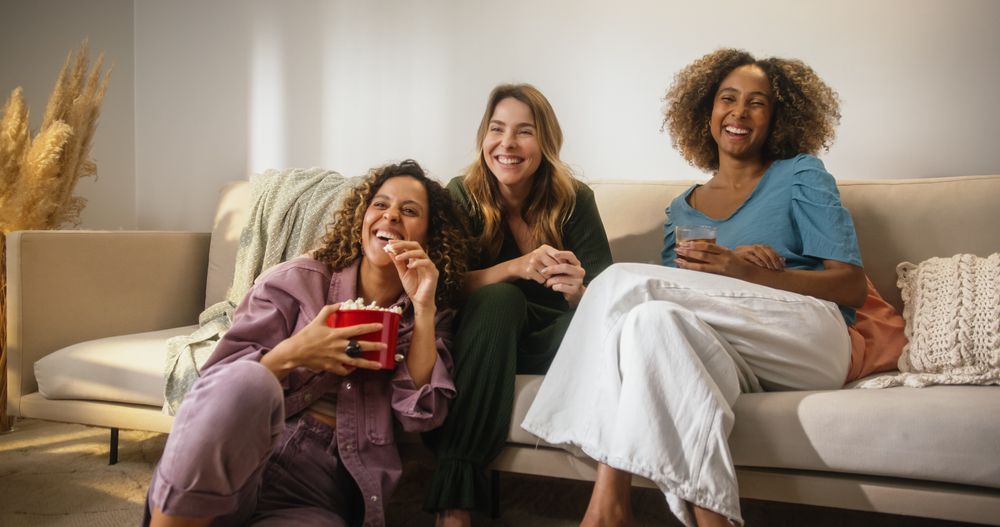 Portrait of Happy Group of Female Friends Watching a Funny Show and Laughing in Cozy Living Room.