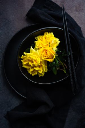 Dark table setting with yellow roses