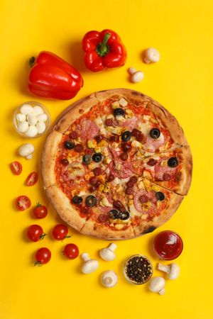 Tasty pizza and ingredients on yellow background