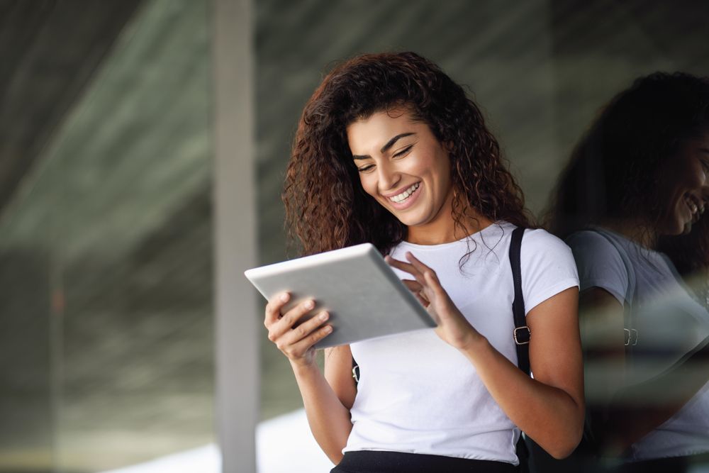 Arab woman looking down at digital tablet in front of office building