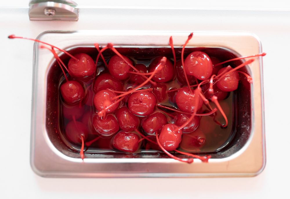 Close up photo of a metal tray filled with cherry toppings on an ice cream parlor counter