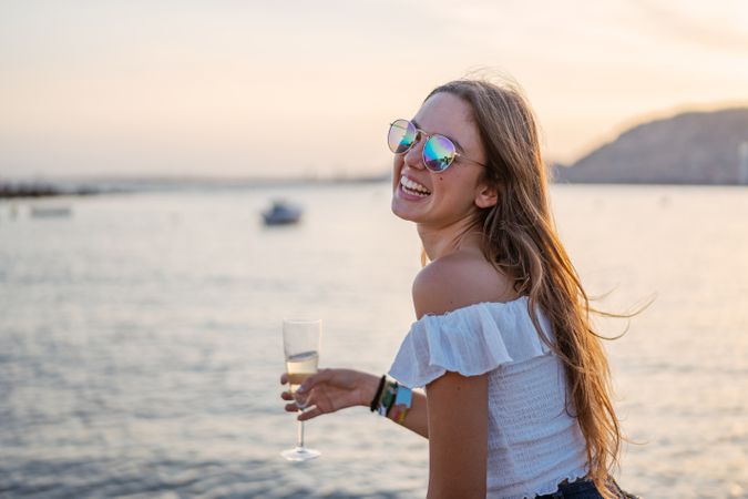 Young woman enjoying wine near sea