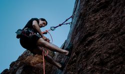 Man holding rope climbing side of mountain