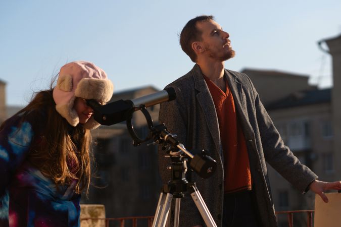 Instructor looks upward while student peers into solar telescope