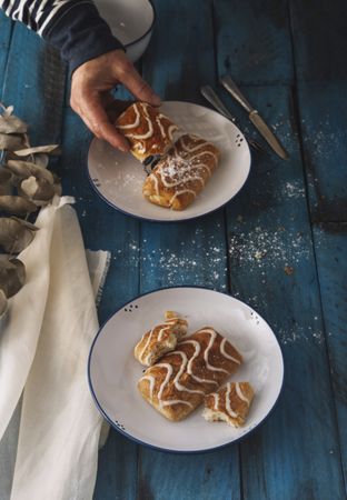 Faceless person taking sweet roll from rustic table