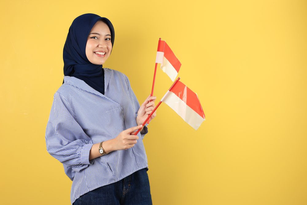 Cheerful Indonesian Muslim Woman in hijab celebrating Independence Day with Flag