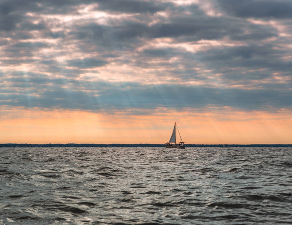 Sailboat amid ocean during sunset
