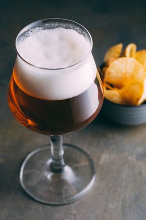 Glass of beer and chips on dark and grunge background