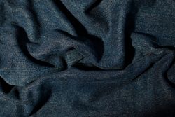 Close up detail crumpled wavy Navy blue jeans fabric background texture.