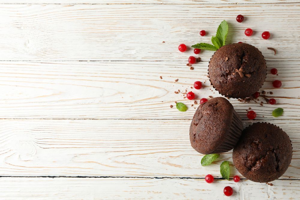 Composition with chocolate muffins and berries on wooden background