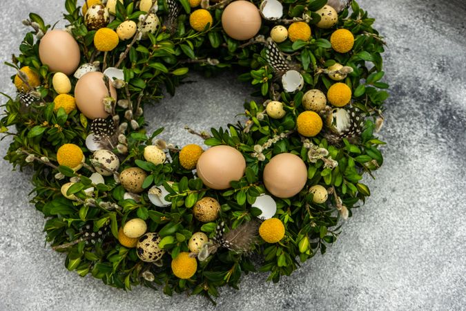Top view Easter card concept with fresh wreath with decorative eggs and feathers