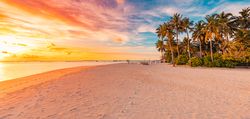 Beach water front under a blue and peach sky at sunset, wide