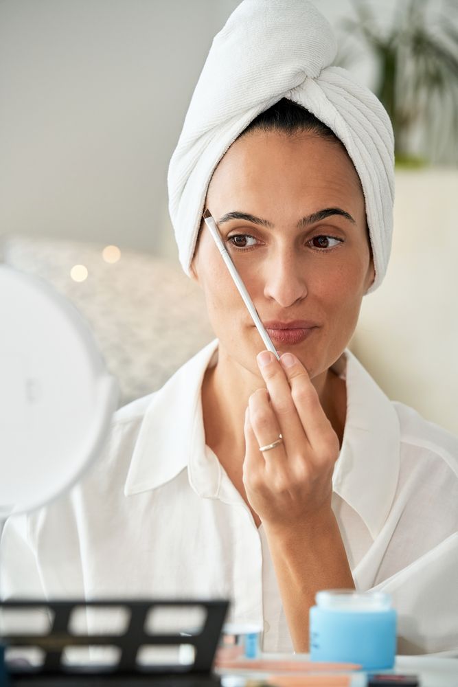 Content woman doing eyebrows makeup