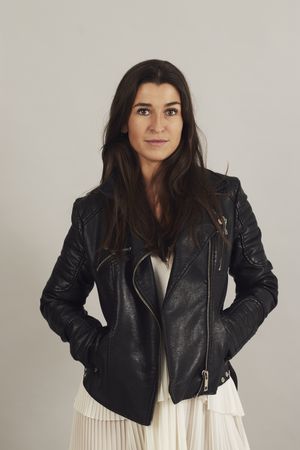 Serious pensive young female wearing leather jacket in studio