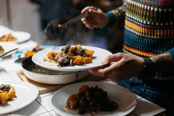 Man in bright sweater plating roasted vegetables