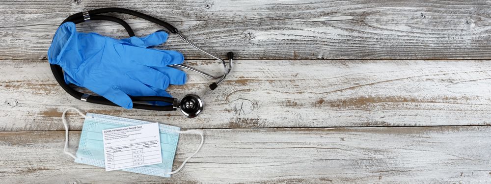 Covid 19 vaccination record card with stethoscope plus latex glove and facemask