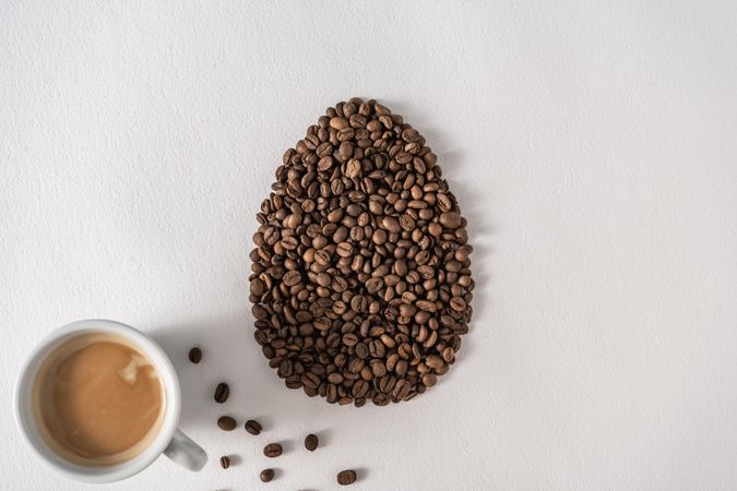 Coffee beans in egg shape with cup of coffee
