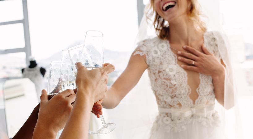 Focus on female hands toasting champagne in wedding clothing shop