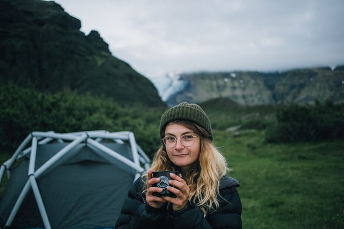 Woman waking up from tent with coffee
