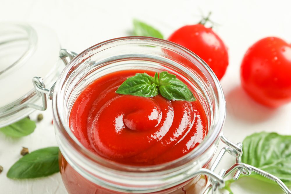 Flat lay composition with fresh tomatoes, basil and sauce in glass jar on blank background, space for text and closeup