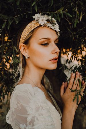Charming woman in elegant dress with flowers near tree