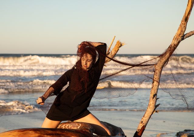 Woman in fishing net fixed on twig near water on shore