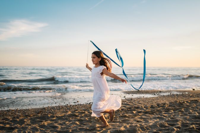 Adorable girl playing with ribbon on seaside
