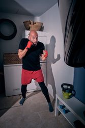 Man training boxing in the laundry room at home with a bag