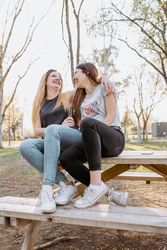 Female friends hugging and laughing in park