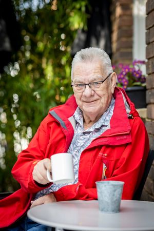 Older man sitting with coffee mug, vertical