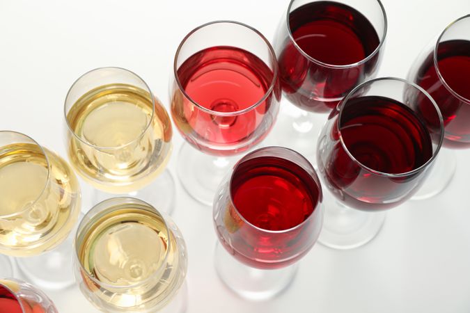Glasses with different wine on blank background, close up
