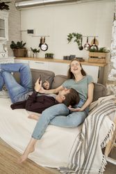 Chilling couple spending time together on sofa browsing smartphone
