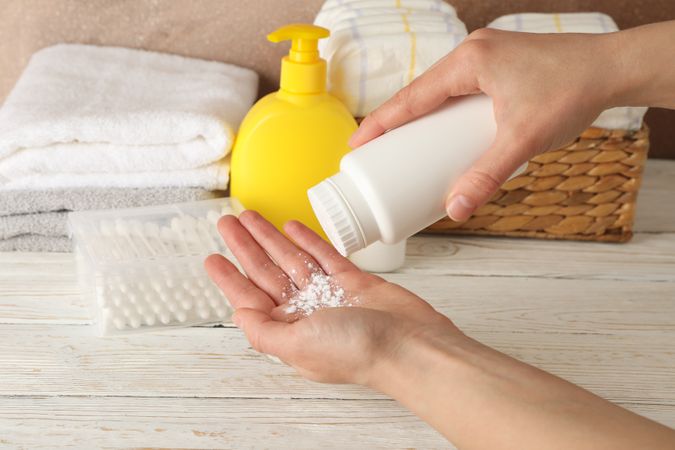 Mom applying talc powder from plastic tube. Baby hygiene