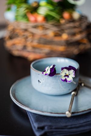 Easter table setting with cup, purple flowers and decorative egg shell
