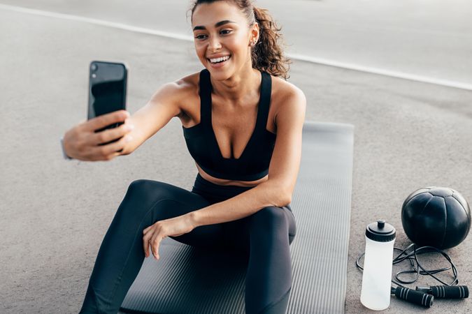 Athletic woman taking selfie on yoga mat