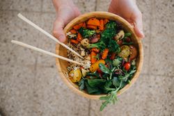 Man holding vegetable bowl and rice