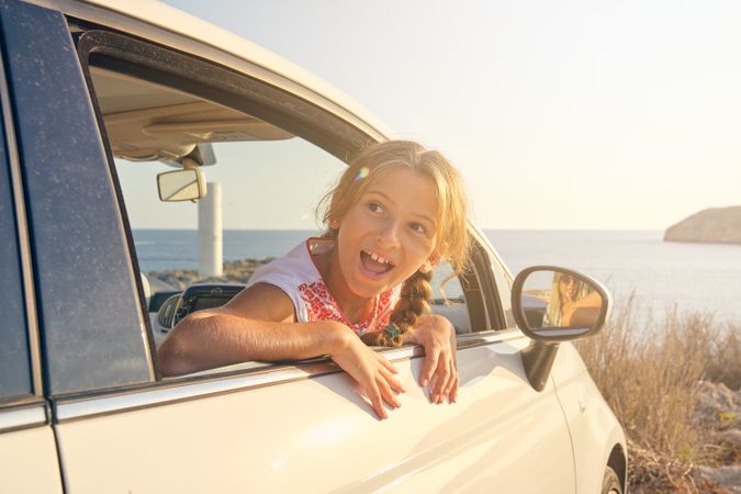 Blonde girl sticking her head out of the window of a car with a