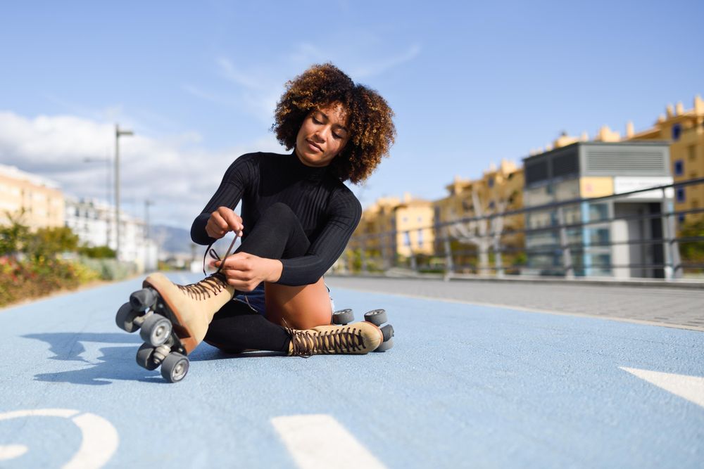 Woman sitting in blue bike lane and putting on roller skates