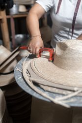 Cutting the brim of a traditional natural fiber hat