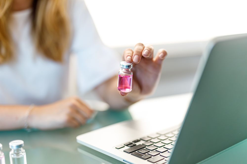 Female working at laptop with medical vials