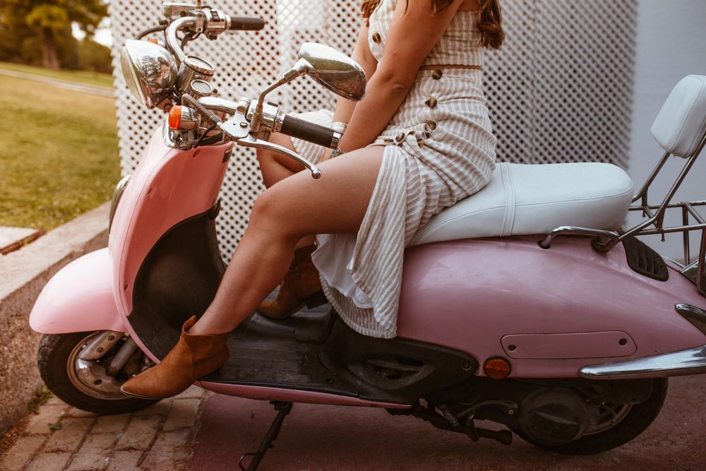 Stylish woman sitting on bike with open leg in beautiful boot