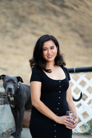 Portrait of woman smiling and looking into camera outside with dog behind