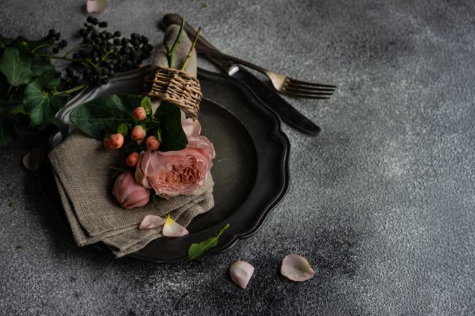 Delicate pink flowers on grey napkin and plate with copy space