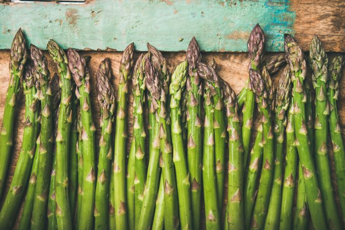 Asparagus lined up on wooden board with green trim, copy space