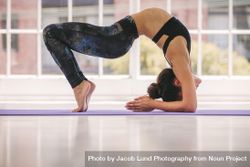 Young female doing bridge yoga pose in gym class 433Kj4