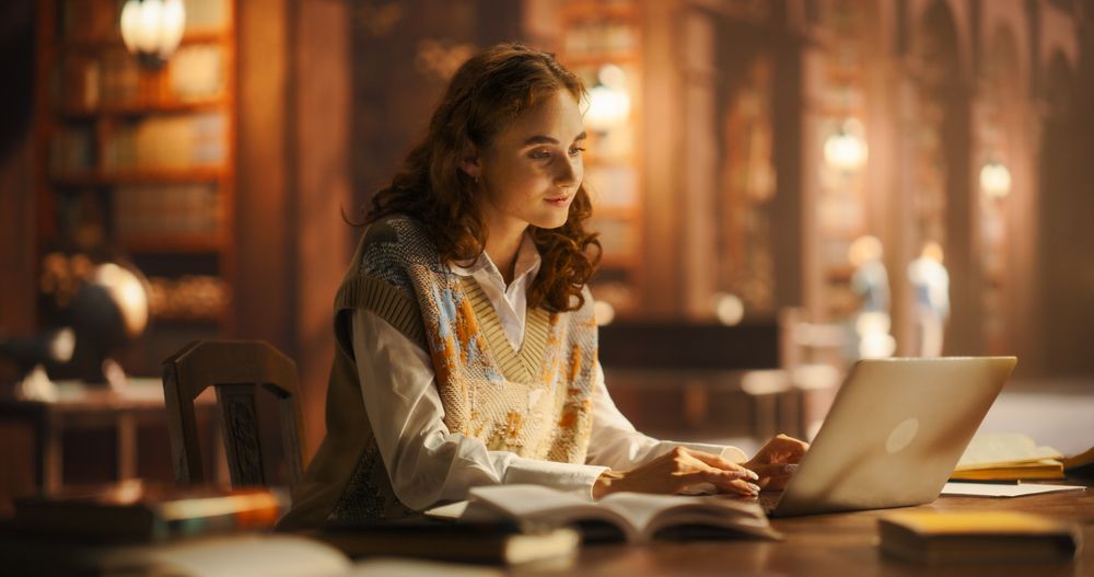 Serene Young Woman Engaged in Studying with Books and Laptop in a Classical Library Setting