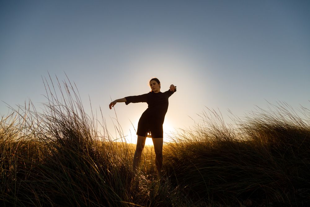 Woman posing between field at sunset