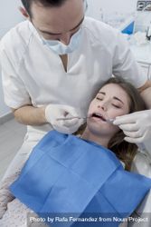 A portrait of a dentist working on the mouth of a female patient, vertical 48VAJ0